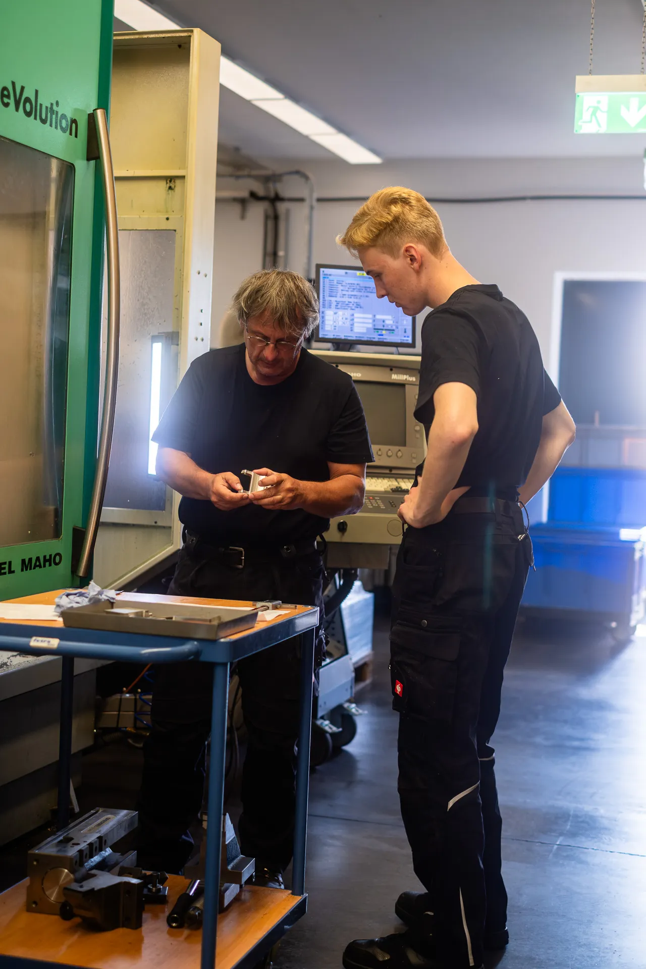 Werkstückkontrolle an der CNC-Fräsmaschine im Austausch zwischen Fachkraft und Nachwuchskraft