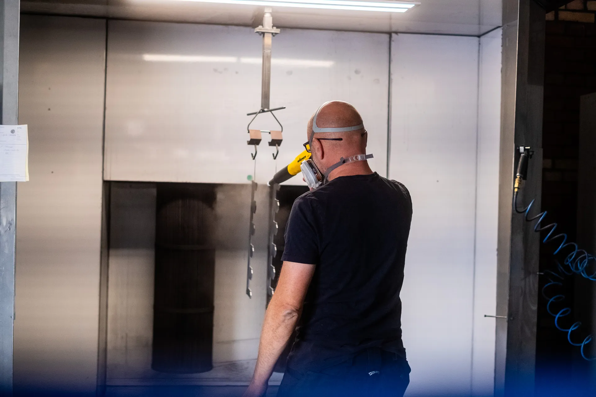 Pulverbeschichtung in der Kabine mit Sprühpistole und Atemschutz