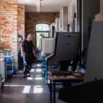 Fertigungsbereich in Backsteinhalle mit CNC-Maschinen, Werkzeugwagen und Arbeitsplätzen