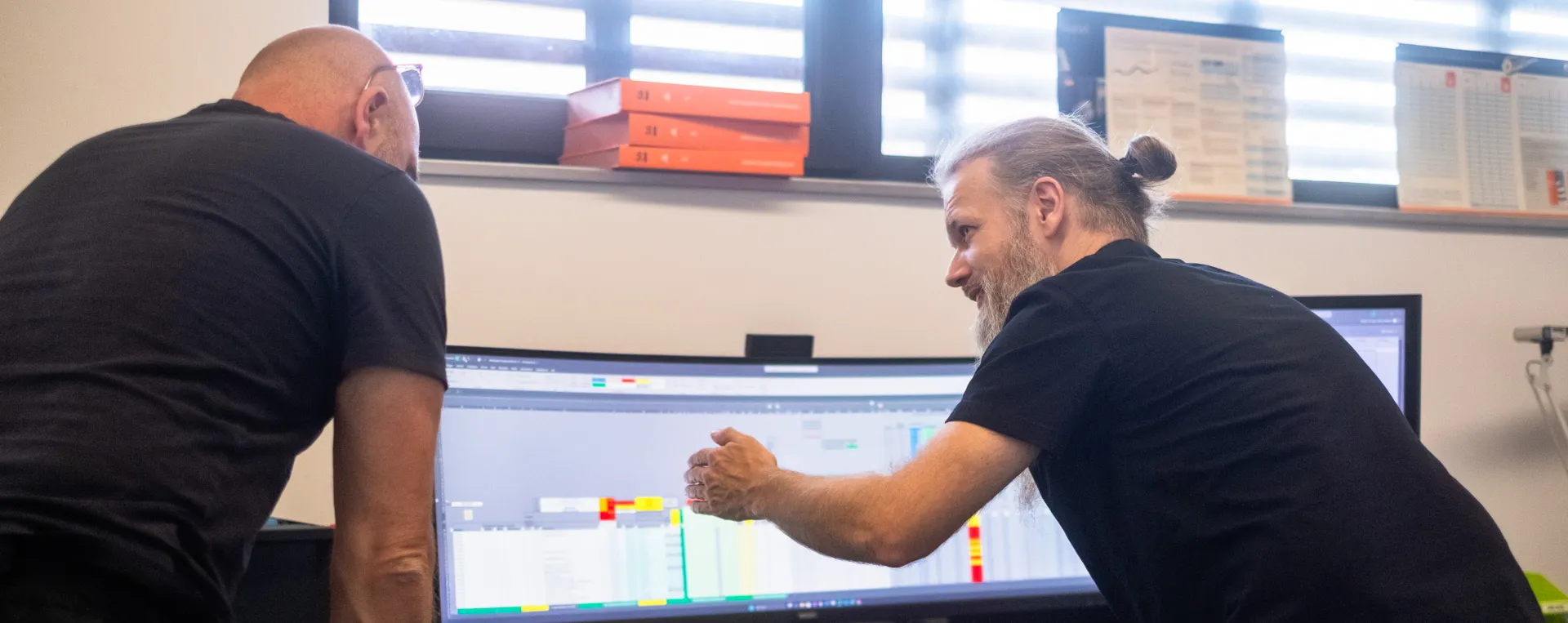 Mitarbeiter besprechen Auftrags- und Kapazitätsplanung am Multi-Monitor-Arbeitsplatz