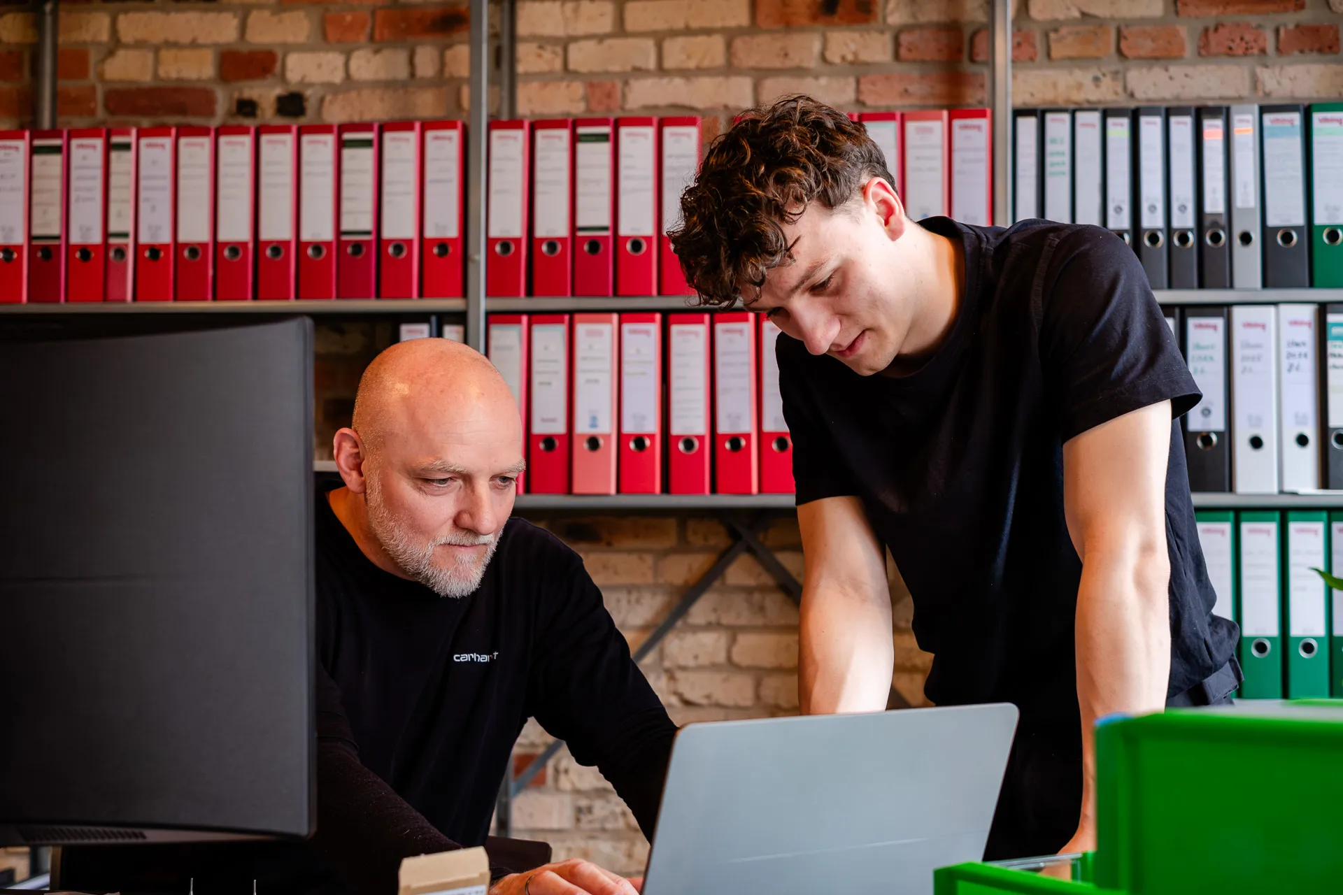 Geschäftsführer und Mitarbeiter besprechen Auftragsdetails am Laptop im Büro von Zonelight